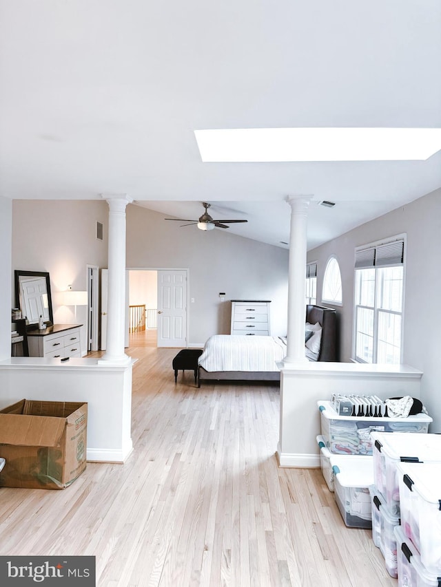 bedroom featuring vaulted ceiling with skylight, decorative columns, visible vents, and wood finished floors