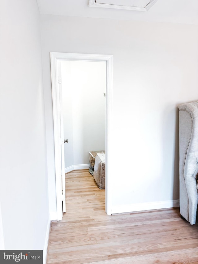 unfurnished bedroom with light wood-style floors, attic access, and baseboards