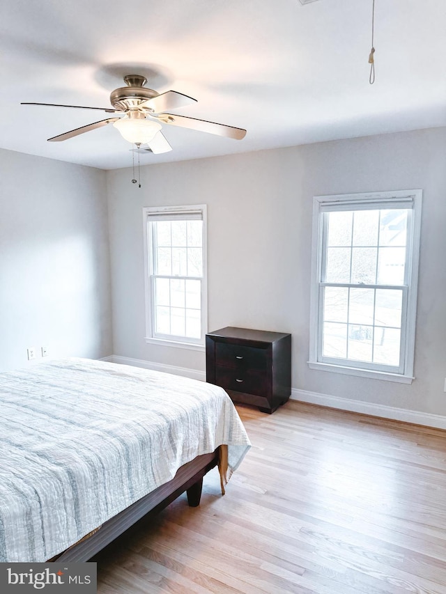 bedroom featuring multiple windows, baseboards, and wood finished floors