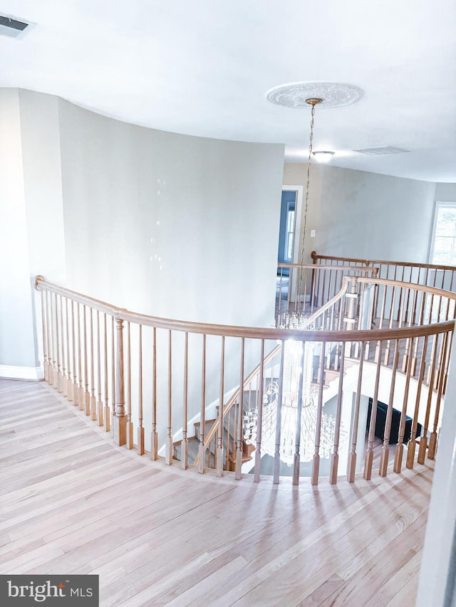 hall featuring an upstairs landing, wood finished floors, and visible vents