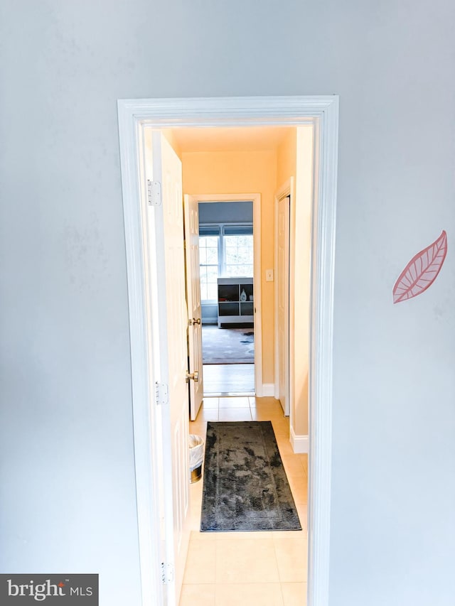 hallway with light tile patterned floors and baseboards