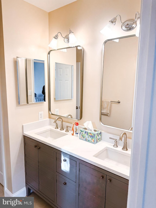 bathroom with a sink, baseboards, and double vanity