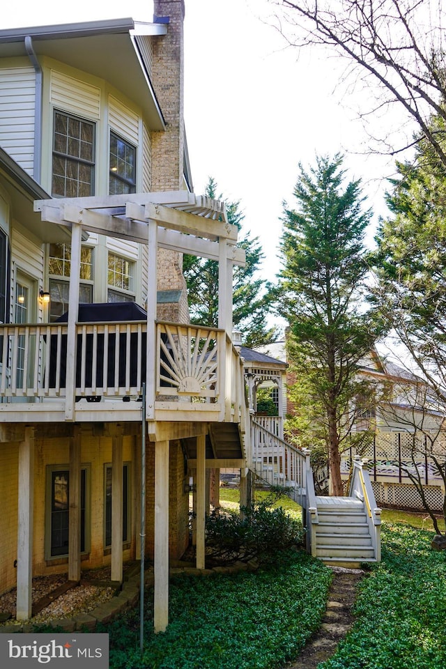 rear view of property with a deck, a chimney, and stairs