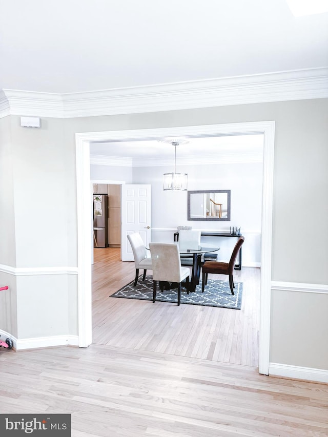 dining room featuring baseboards, an inviting chandelier, wood finished floors, and crown molding