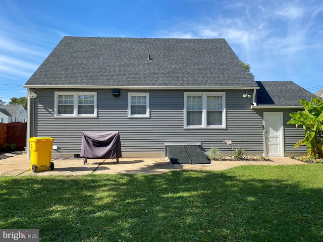 rear view of house featuring a patio, a lawn, fence, and roof with shingles