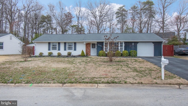 single story home with aphalt driveway, fence, board and batten siding, a front yard, and an attached garage