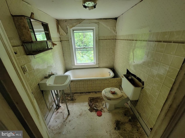 full bathroom featuring a sink, tile walls, toilet, and a bath