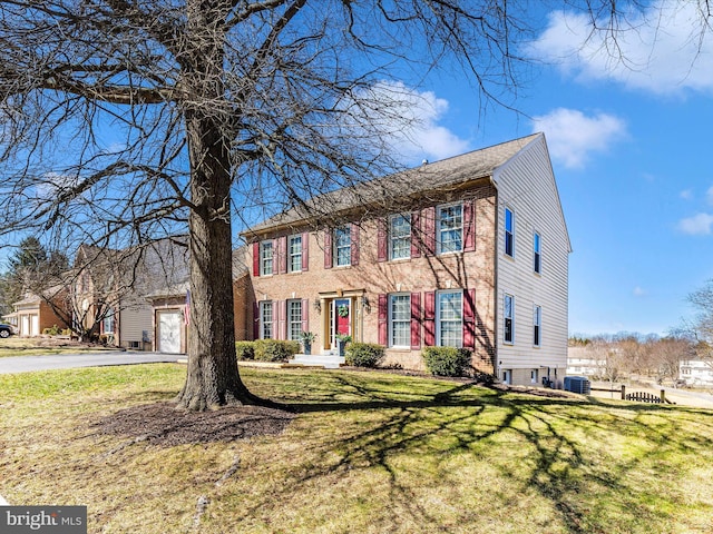 colonial home featuring a front lawn, central air condition unit, and aphalt driveway