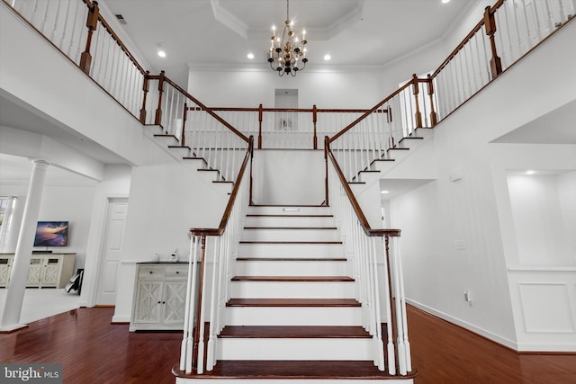 stairway featuring a towering ceiling, baseboards, ornamental molding, and wood finished floors