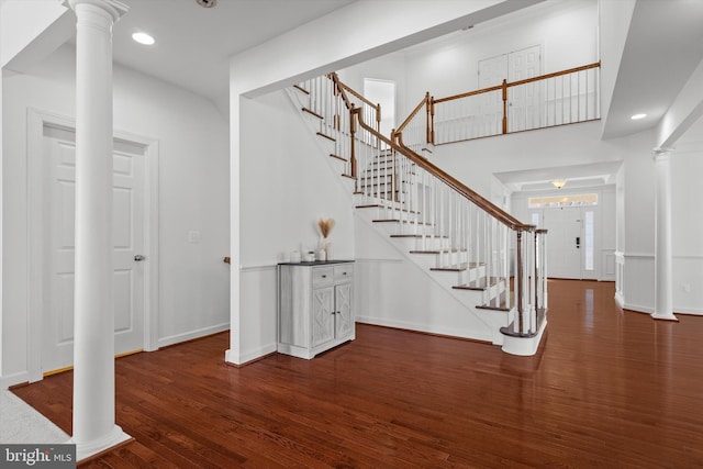 entrance foyer featuring stairs, baseboards, wood finished floors, and ornate columns