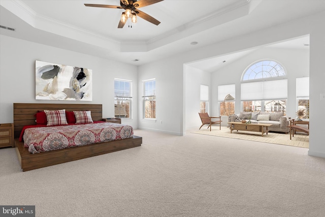 carpeted bedroom featuring a tray ceiling, crown molding, visible vents, a ceiling fan, and baseboards