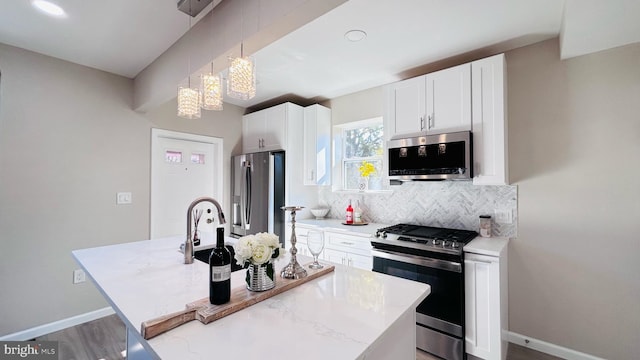 kitchen featuring a center island with sink, hanging light fixtures, stainless steel appliances, white cabinetry, and backsplash