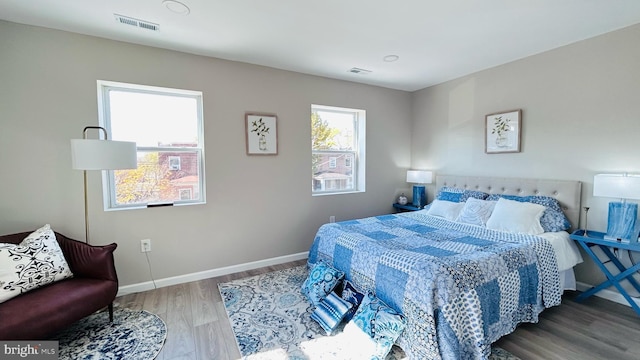 bedroom with visible vents, baseboards, and wood finished floors