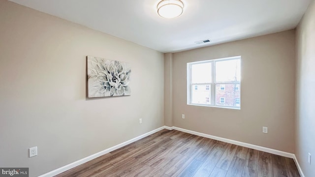 unfurnished room with baseboards, visible vents, and wood finished floors