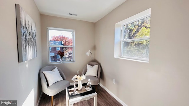 living area with dark wood-type flooring, a healthy amount of sunlight, visible vents, and baseboards