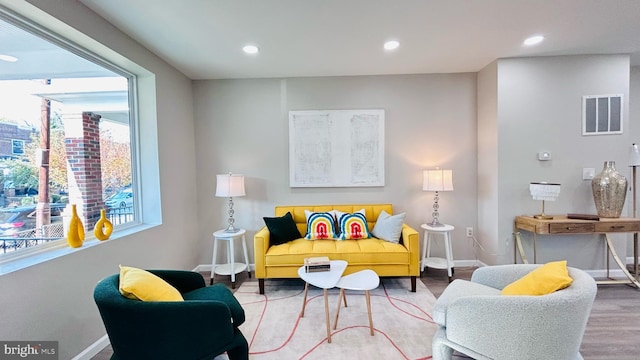 living area with baseboards, visible vents, wood finished floors, and recessed lighting