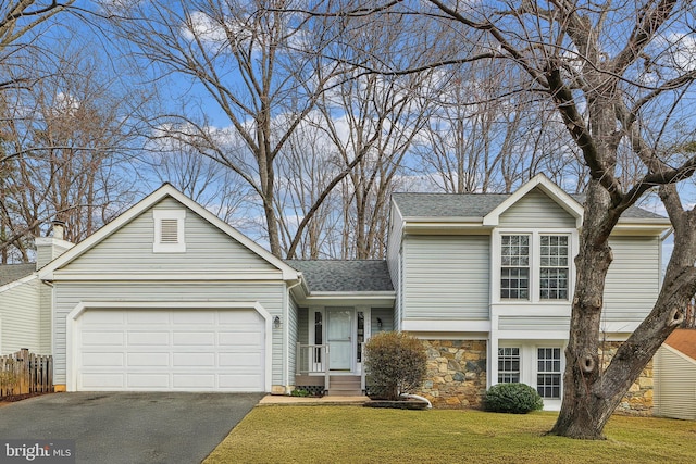 split level home with driveway, stone siding, roof with shingles, a front yard, and an attached garage