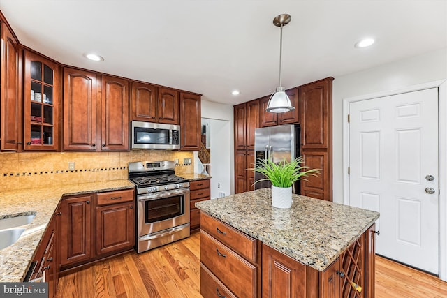 kitchen with light stone counters, stainless steel appliances, glass insert cabinets, light wood-type flooring, and backsplash