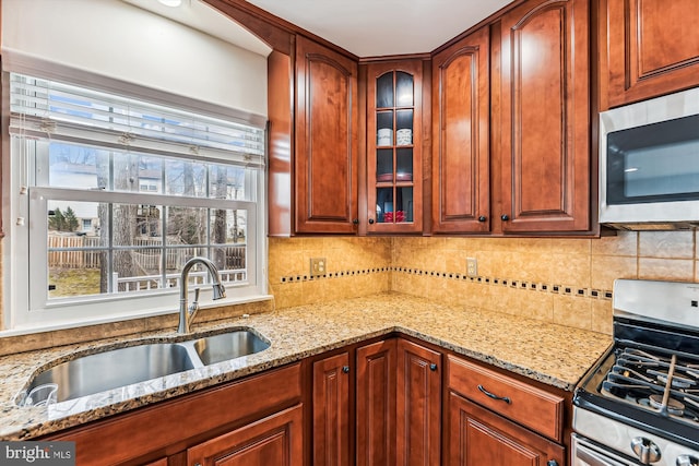 kitchen featuring a sink, decorative backsplash, light stone counters, and appliances with stainless steel finishes