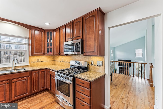 kitchen featuring plenty of natural light, appliances with stainless steel finishes, light stone countertops, and a sink