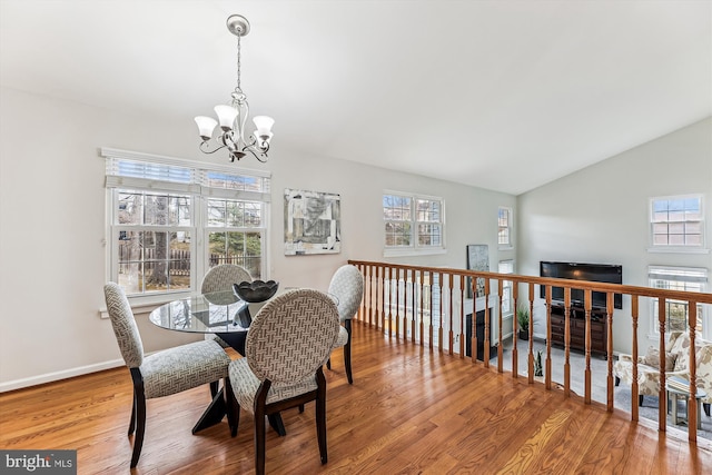 dining area featuring vaulted ceiling, a notable chandelier, baseboards, and wood finished floors