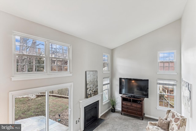 living area featuring baseboards, carpet floors, lofted ceiling, and a fireplace with flush hearth