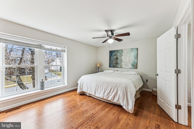 bedroom with visible vents, baseboards, wood finished floors, and a ceiling fan