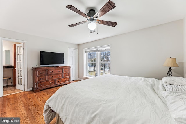 bedroom featuring ensuite bathroom, a ceiling fan, baseboards, and light wood finished floors