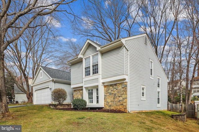 view of home's exterior with a garage, a yard, fence, and stone siding