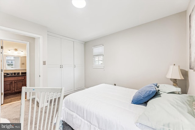 bedroom featuring a sink, a closet, light carpet, and ensuite bathroom