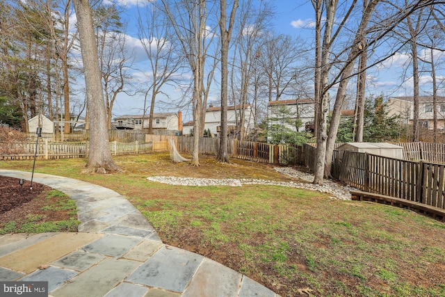 view of yard with an outdoor structure, a fenced backyard, and a residential view