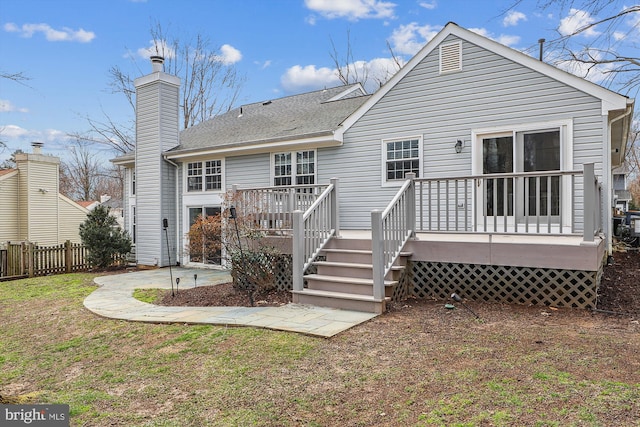 rear view of house with a lawn, fence, a chimney, and a wooden deck