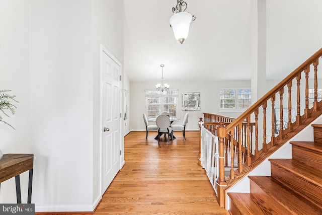 entryway featuring stairway, baseboards, a notable chandelier, and light wood-style flooring