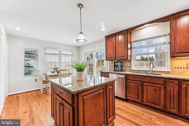 kitchen with stainless steel dishwasher, decorative backsplash, light wood finished floors, and a sink