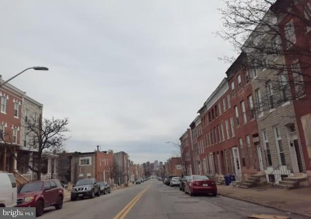 view of road featuring sidewalks, entry steps, curbs, and street lights