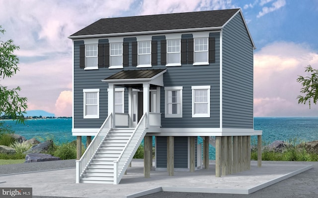 beach home with stairs, a shingled roof, and a water view