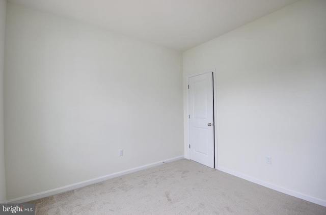 spare room with baseboards and light colored carpet