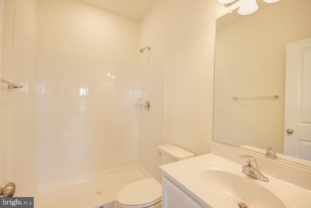 full bath featuring toilet, tiled shower, and vanity