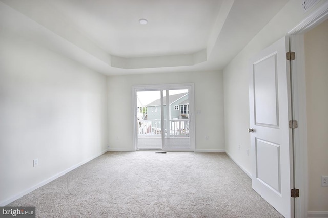 unfurnished room featuring baseboards, a raised ceiling, and light colored carpet