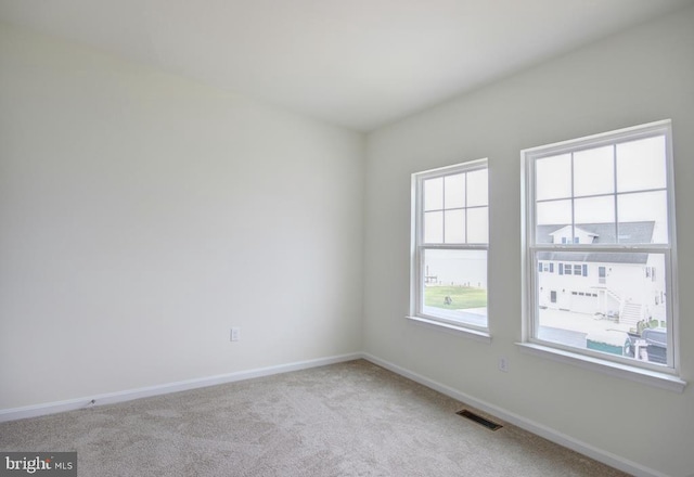 empty room with light colored carpet, visible vents, and baseboards