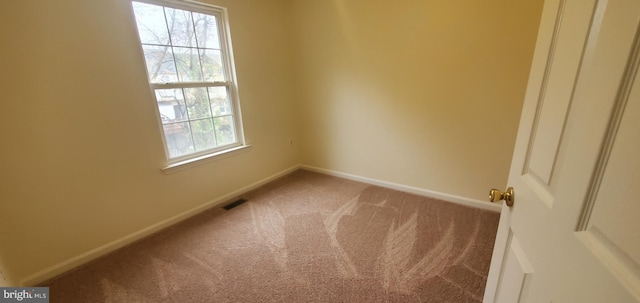 empty room featuring carpet, visible vents, and baseboards