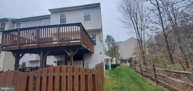 rear view of house with fence, a deck, and a lawn