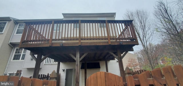 rear view of house with a deck, fence, and a gate