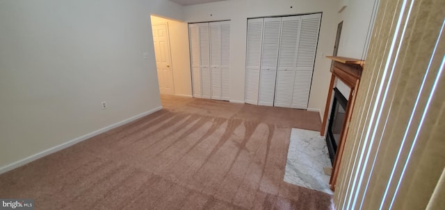 unfurnished living room with light colored carpet, a fireplace, and baseboards