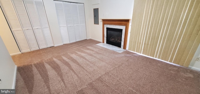 unfurnished living room with a high end fireplace, electric panel, and light colored carpet