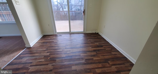 spare room with dark wood-style flooring, a healthy amount of sunlight, and baseboards