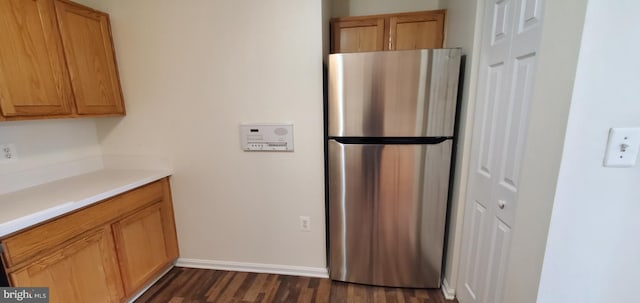 kitchen featuring baseboards, light countertops, dark wood-style flooring, and freestanding refrigerator