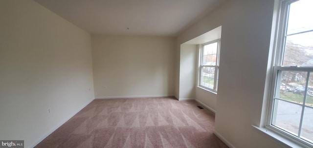 empty room featuring baseboards, visible vents, and light colored carpet