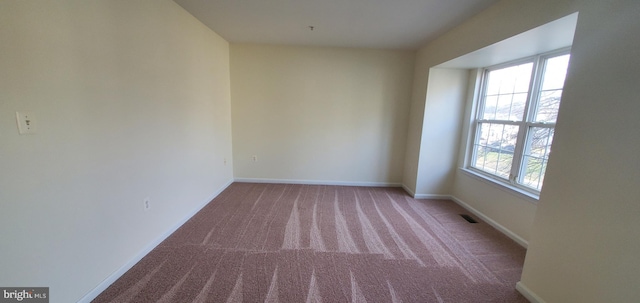 empty room featuring baseboards, visible vents, and light colored carpet