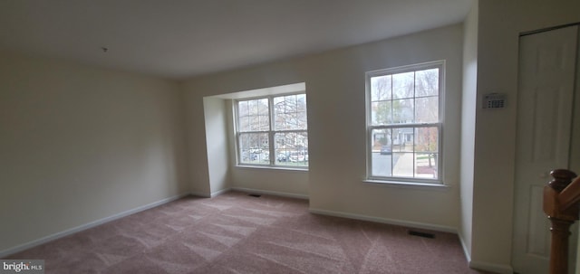 unfurnished room with light carpet, visible vents, and baseboards